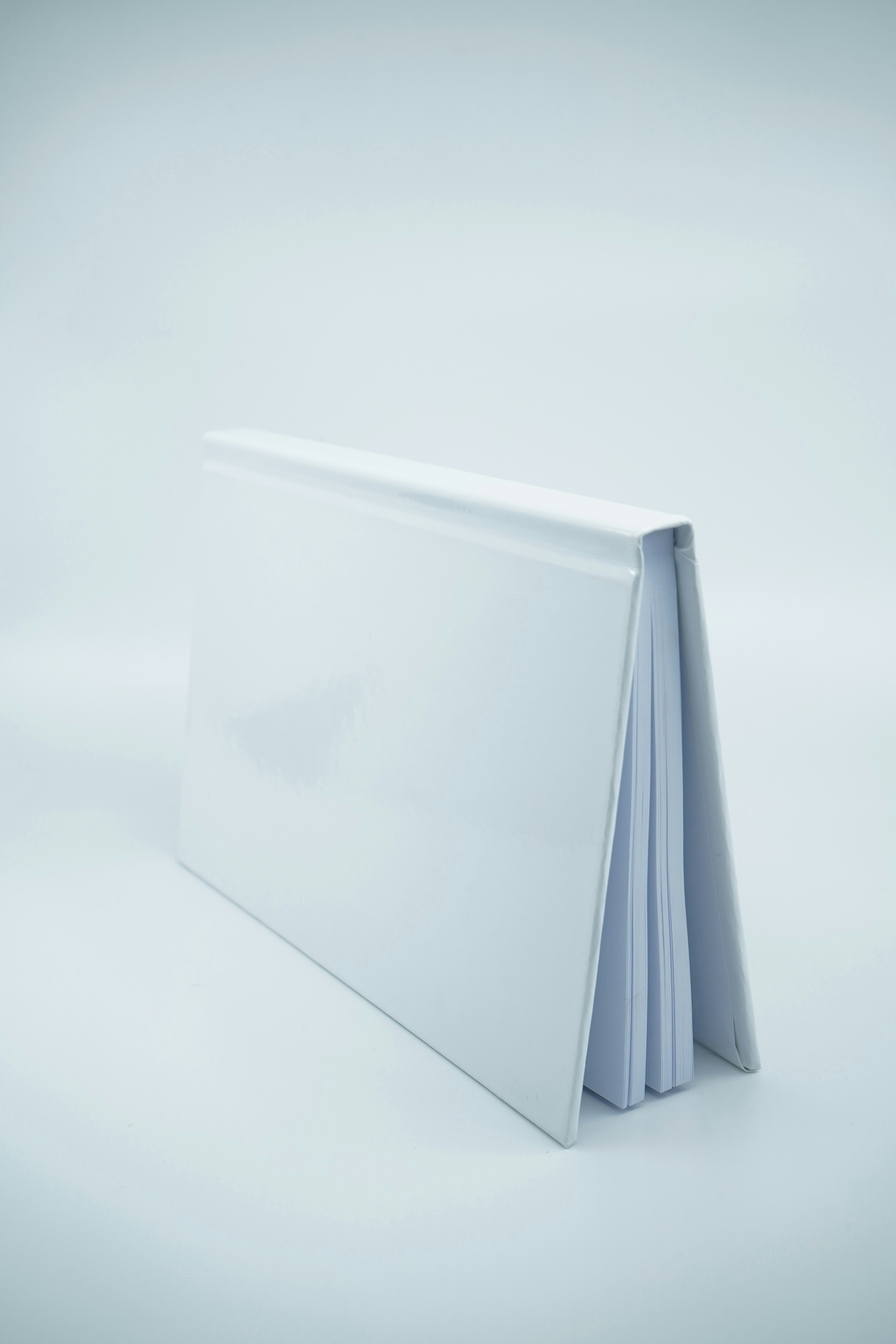 Minimal style photo featuring a blank hardcover white book mockup on a gray studio background scene.